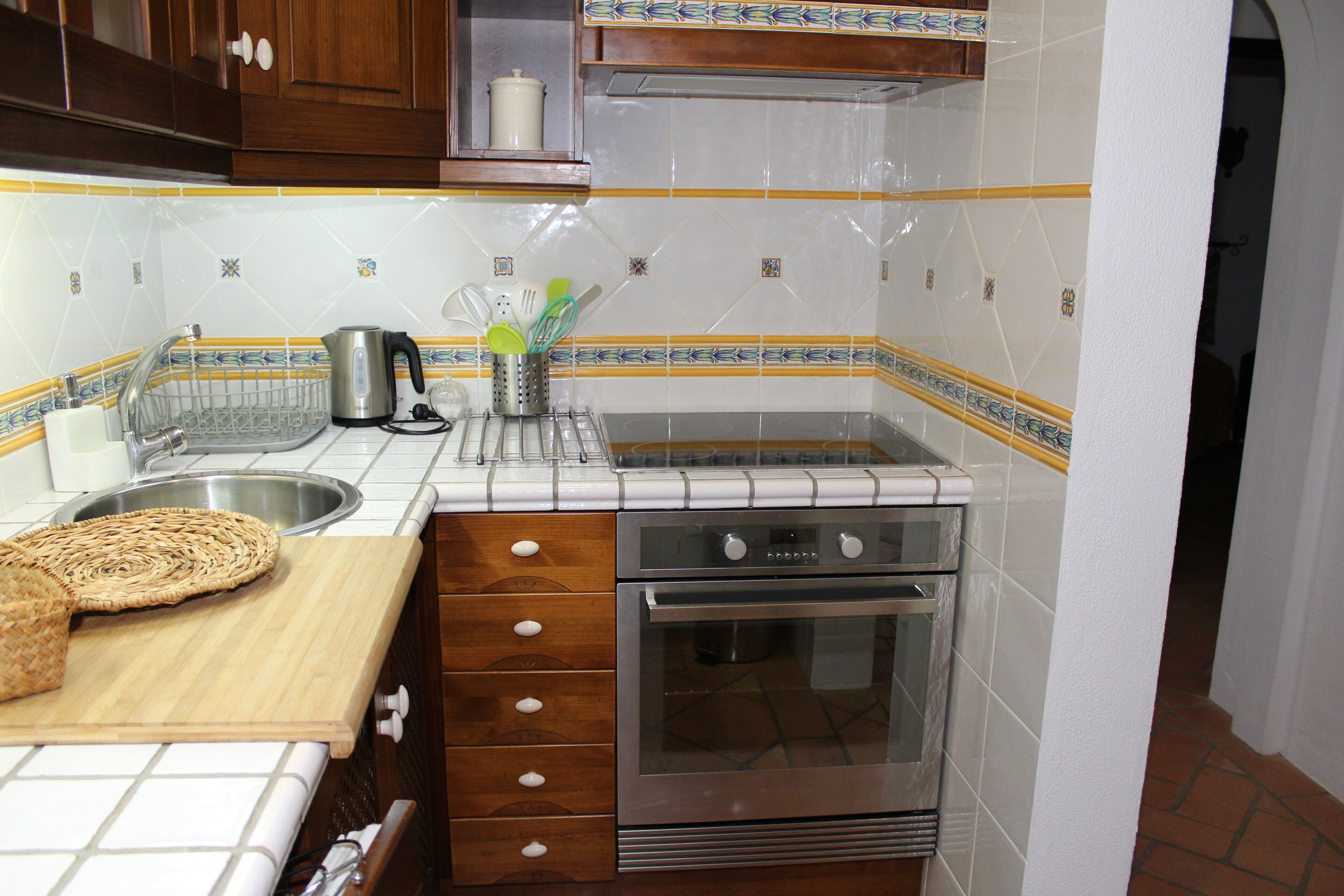 A kitchen with a stainless steel oven, a sink, and a wooden countertop.