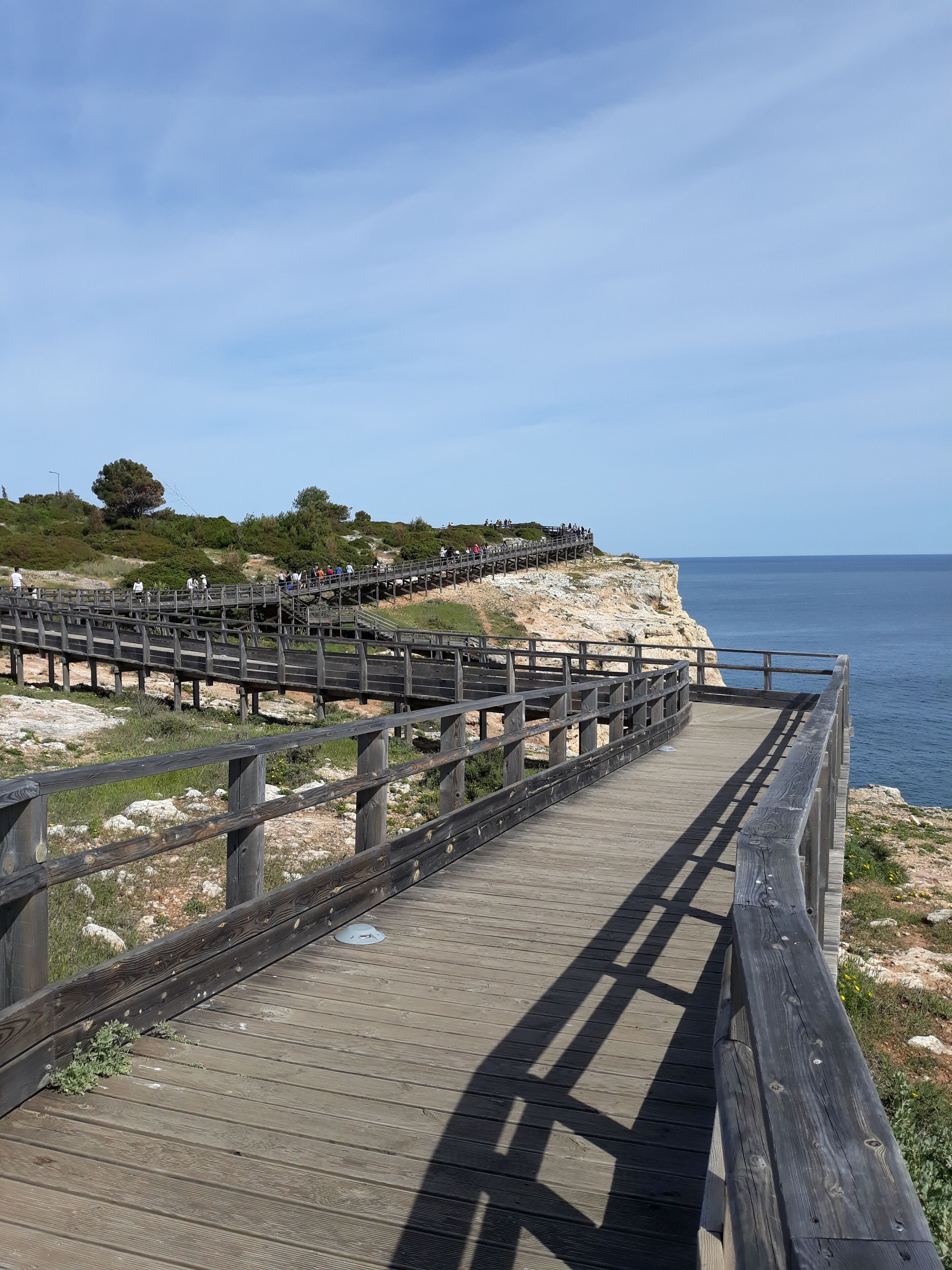 Un paseo marítimo de madera que conduce a un acantilado con vista al mar.
