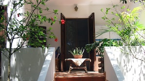 Un escalier menant à une porte, avec une plante en pot posée sur une petite table en haut.