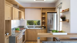 A modern kitchen with wooden cabinets, stainless steel appliances, and a window providing natural light. - Kozanitis Brand New Exclusive Villa With Private Pool (Agrikies Villas) (Lefkada)