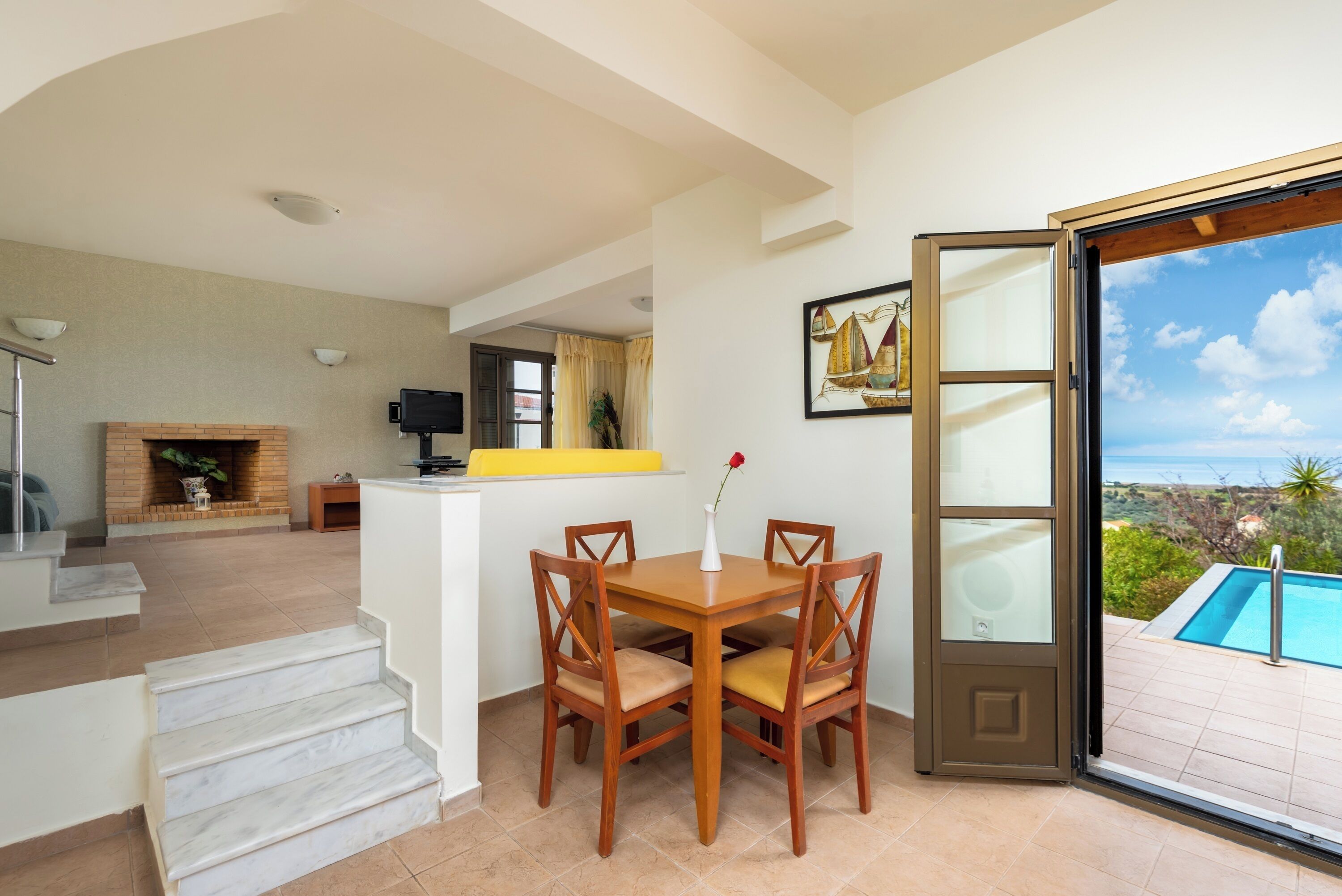 A dining area with a table and chairs, a fireplace, and a view of a swimming pool.