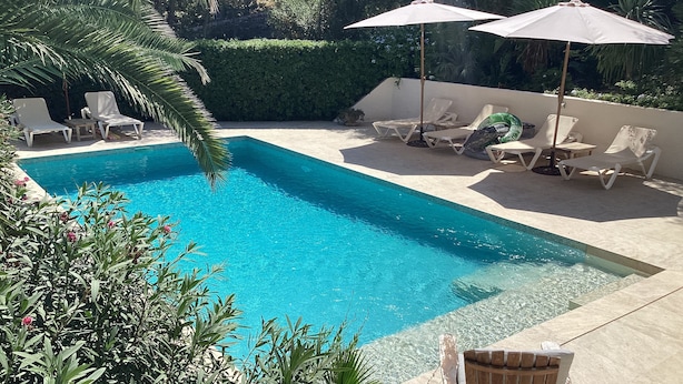 A swimming pool with lounge chairs and umbrellas. - Private villa with mature gardens, 2 minutes walk from sandy beach. (sant lluis)