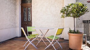 Une terrasse avec une table ronde et deux chaises, une plante en pot et une porte décorative.