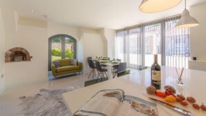 A modern living room with a fireplace, a dining area with a table set for four, and a large window with blinds. - Tun House, Letheringsett, Norfolk (Letheringsett)