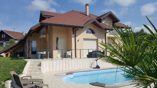 Ein zweistöckiges Haus mit Swimmingpool, überdachter Terrasse und Garten.
