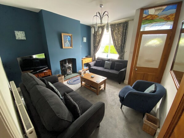 A living room with a sofa, armchair, TV, fireplace, and a window with curtains.