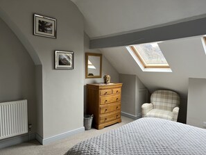 A bedroom with a sloped ceiling, a wooden dresser, a plaid chair, and two framed pictures on the wall. - ⭐️⭐️⭐️⭐️⭐️ Outstanding refurbished home in the heart of Coniston Village (Coniston)