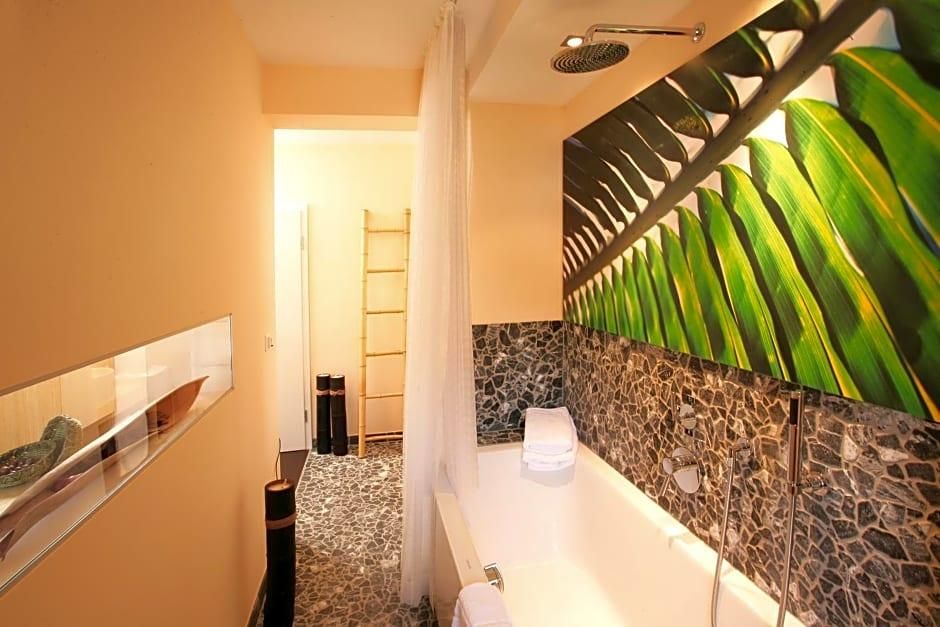 Een badkamer met een badkuip, douche en een decoratieve wand met een bladmotief.