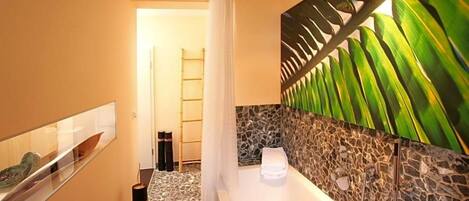 Un bagno con vasca, doccia e una parete decorata con un motivo a foglia.