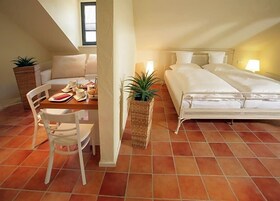 Un dormitorio con cama, mesita de noche, silla y una pequeña zona de comedor con mesa y sillas.
