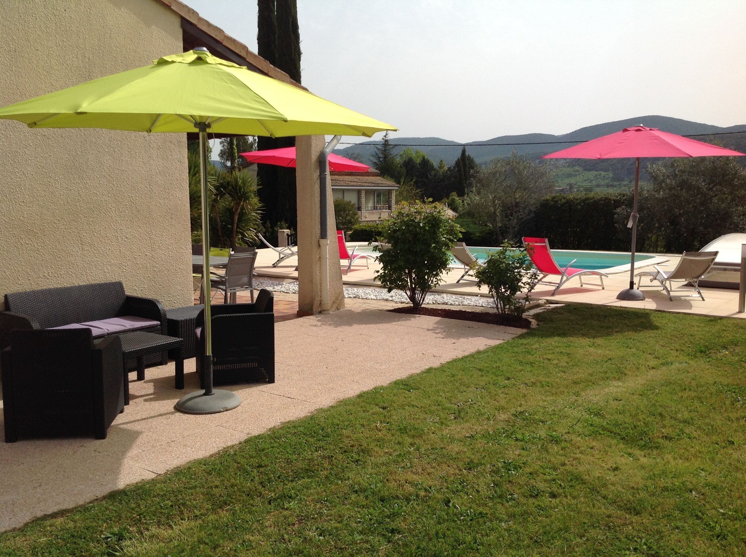 Un'area patio con mobili da esterno, ombrelloni e una piscina.