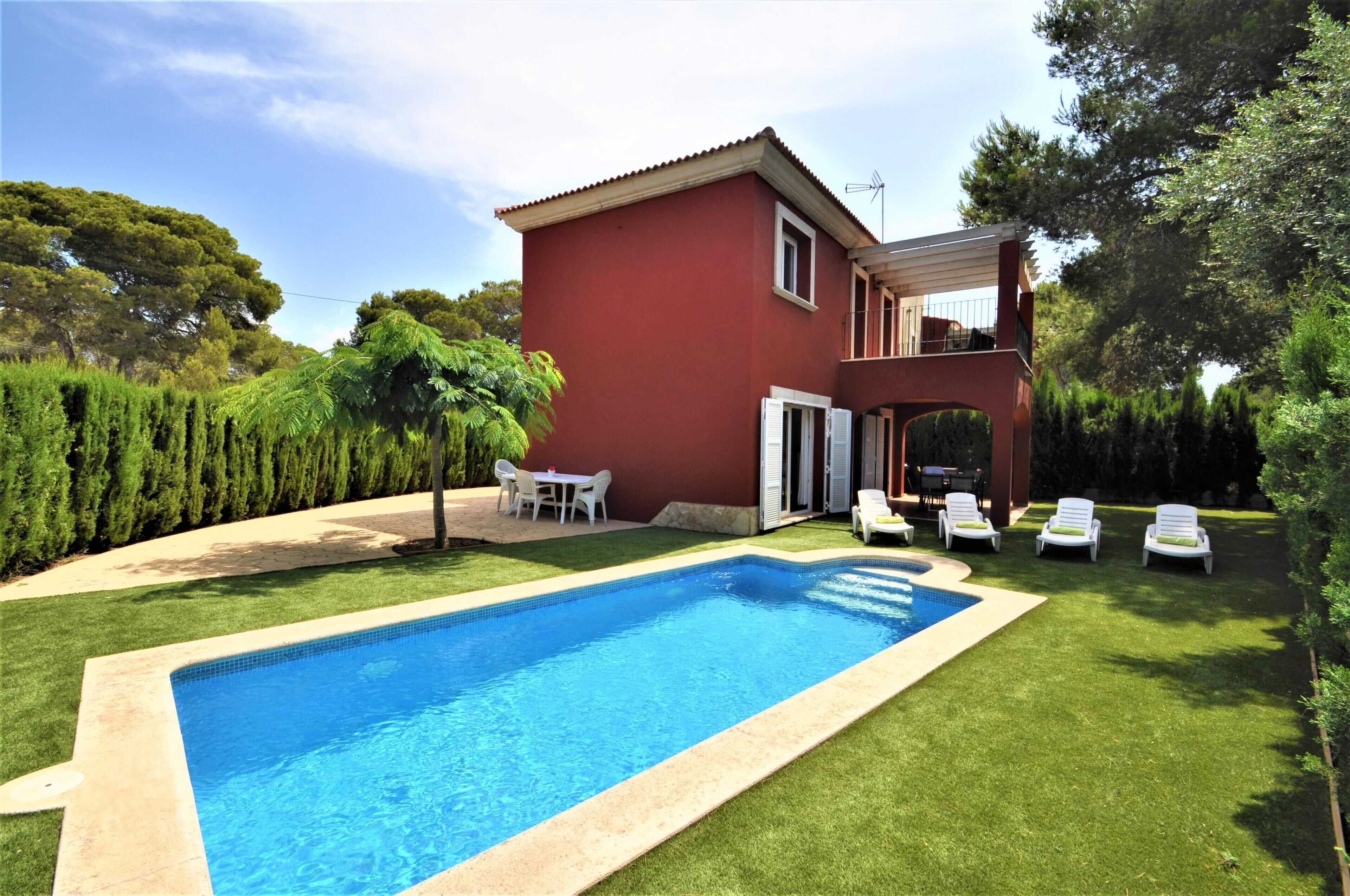 A red house with a swimming pool and outdoor seating.