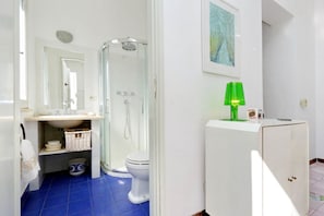 Une salle de bain équipée d’une douche, de toilettes, d’un lavabo et d’un meuble de rangement.