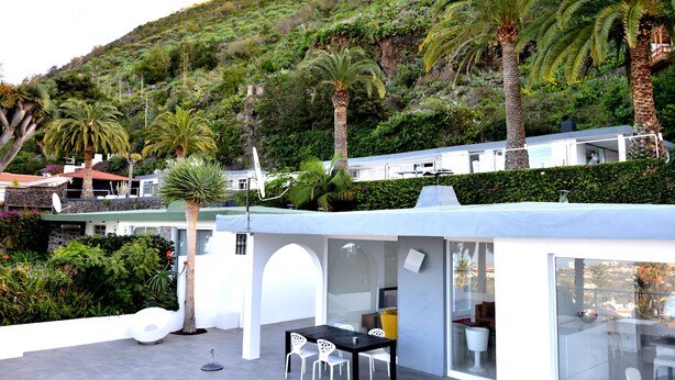 Eine moderne Außenpatio mit Glasveranda, weißen Stühlen und einem Esstisch.