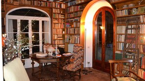Una biblioteca acogedora con estanterías, una mesa de madera y una silla.