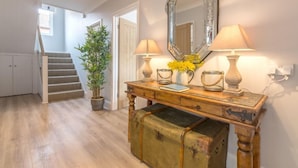 A hallway with a wooden bench, a mirror, and a lamp. There is a staircase in the background. - Kipling House (8), Wells-next-the-Sea, Norfolk (Wells-next-the-Sea)