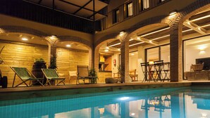 Ein Swimmingpool mit Liegestühlen, einer Ziegelssäule und einer Holzwand.