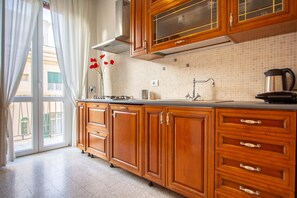 A kitchen with wooden cabinets, a stainless steel sink, and a window with curtains.