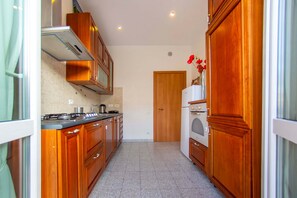A kitchen with wooden cabinets, a stove, and a refrigerator. - Lovely Sea View Apartment Lido di Ostia, 30 minutes from  center of Rome, Wi-Fi (Lido di Ostia)