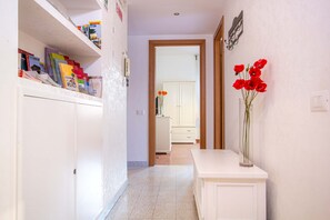 A hallway with a white cabinet on the left, a white console table on the right, and a door leading to a room with a white cabinet.