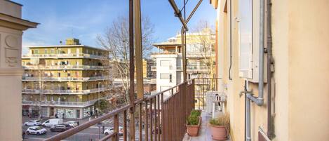 A balcony with a view of a parking lot and buildings.