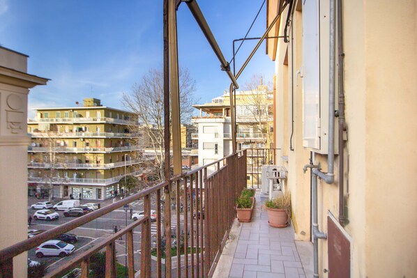 A balcony with a view of a parking lot and buildings.