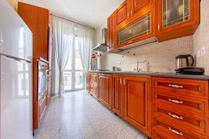A kitchen with wooden cabinets, a stainless steel sink, and a kettle on the counter. - Lovely Sea View Apartment Lido di Ostia, 30 minutes from  center of Rome, Wi-Fi (Lido di Ostia)