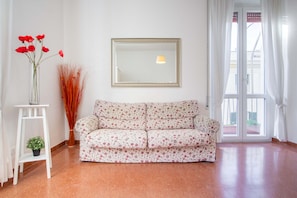A room with a sofa, a mirror, a vase with red flowers, and a potted plant. - Lovely Sea View Apartment Lido di Ostia, 30 minutes from  center of Rome, Wi-Fi (Lido di Ostia)
