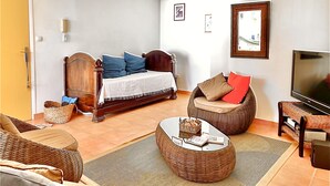 Une chambre à coucher avec un lit, une télévision, des meubles en osier et un ventilateur de plafond.