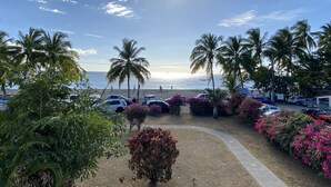 Un parking situé au bord de la plage, agrémenté de palmiers et d’arbustes en fleurs, qui mène à l’océan.