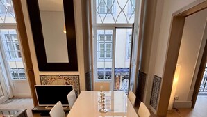 A modern dining area with a large white table, four chairs, and a decorative candle centerpiece.