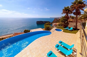 Une piscine avec vue sur la mer et les falaises rocheuses.