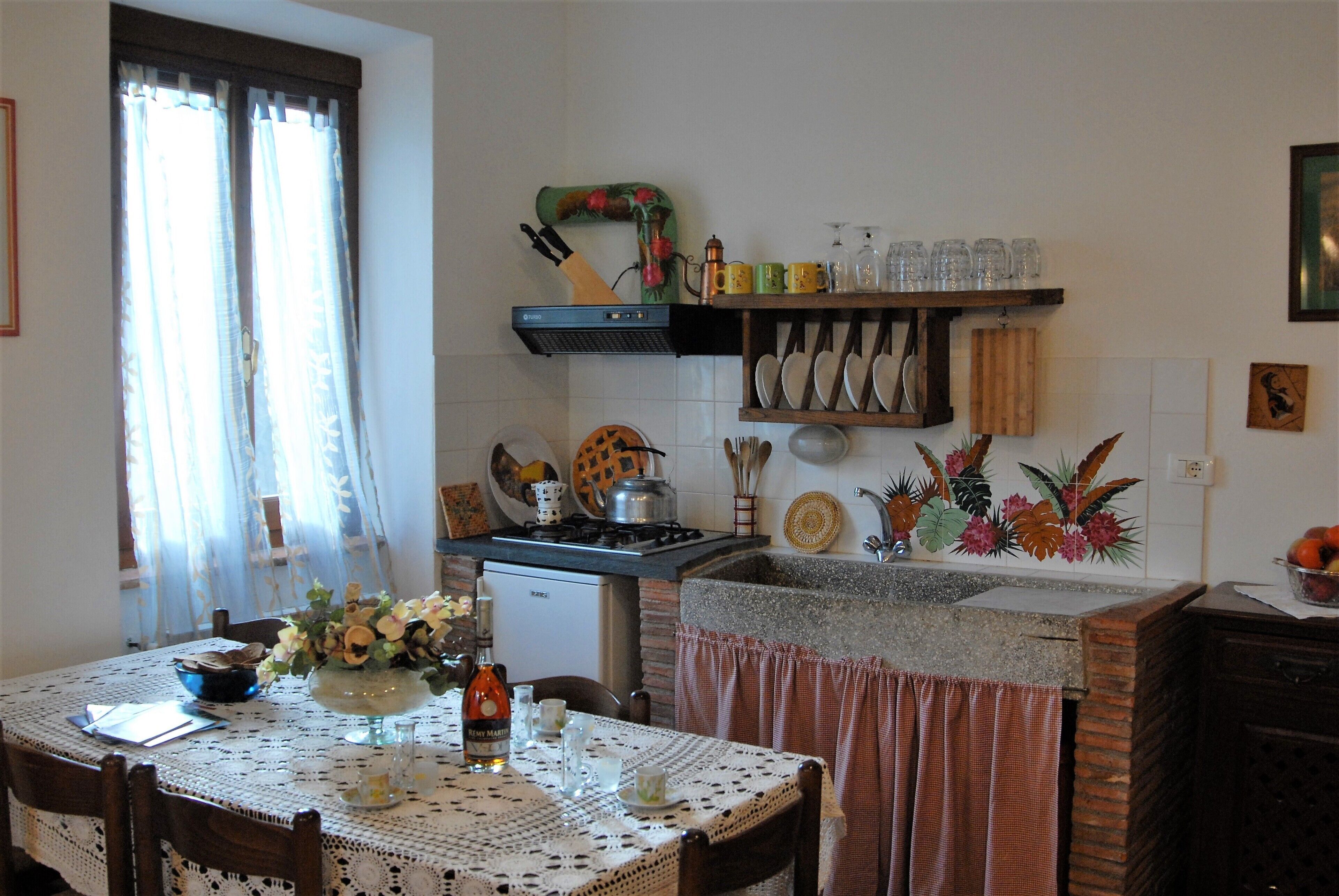 Una cocina con una mesa dispuesta para comer, una cafetera y diferentes utensilios de cocina.