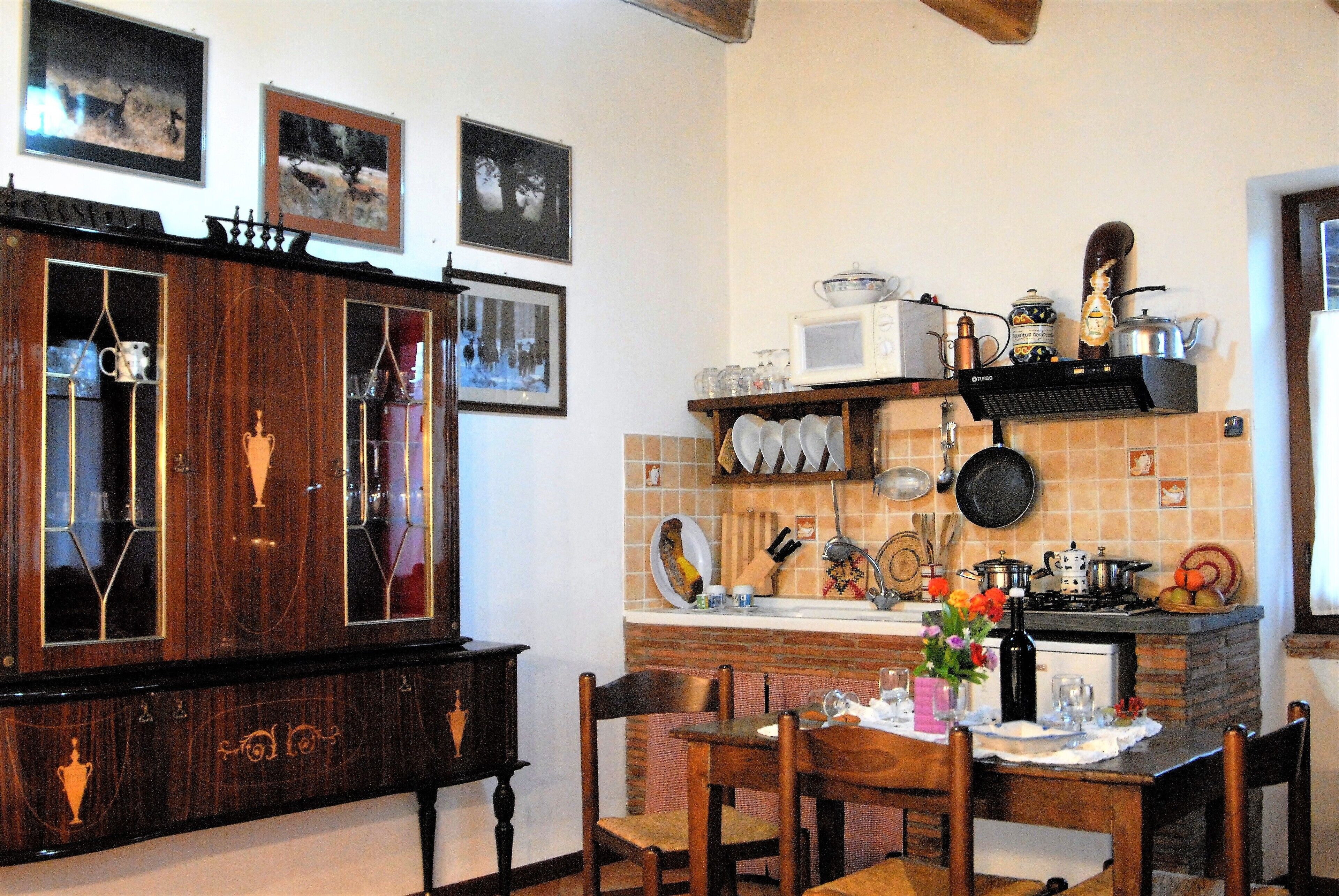 A kitchen with wooden cabinets, a dining table set for four, and a tiled backsplash.
