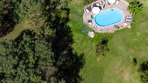 Eine Luftaufnahme eines Anwesens mit Schwimmbad, Stein-Terrasse und einem Haus mit Ziegeldach.