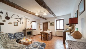 Ein gemütliches Wohnzimmer mit Kamin, eine Essecke mit Tisch und Stühlen sowie eine Küchenzeile mit Herd.