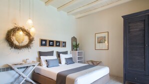Un dormitorio con cama, mesitas de noche, cómoda y cuadros colgados en la pared.