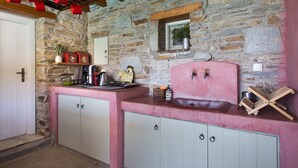 Una cocina rústica con paredes de piedra, encimera rosa y armarios de madera.