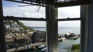 A view from a window overlooking a harbor with buildings, boats, and a clear sky. - Beautiful 2 bed apartment, tastefully furnished with breathtaking views. (LOOE         CORNWALL)