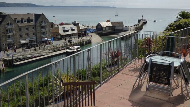 A balcony with a view of a harbor, including boats and buildings. - Beautiful 2 bed apartment, tastefully furnished with breathtaking views. (LOOE         CORNWALL)