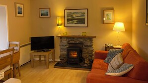 A cozy living room with a stone fireplace, a television, a sofa, and framed pictures on the wall. - Isle of Skye Butt & Beinne for (second !) honeymooners or, getting away (Breakish)