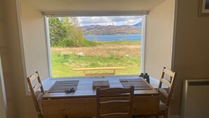 A dining table with four chairs, a view of a lake and mountains, and a wooden bench outside. - Isle of Skye Butt & Beinne for (second !) honeymooners or, getting away (Breakish)