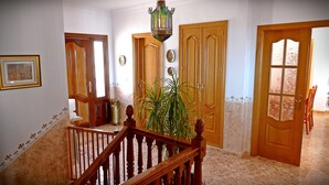 Ein Flur mit Holztüren, einer Treppe und einem Topfpflanzen.