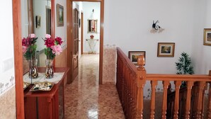Ein Flur mit einer Holztreppe, einem Spiegel und einer Blumenvase.