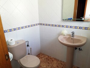 Een badkamer met toilet, wastafel en spiegel.