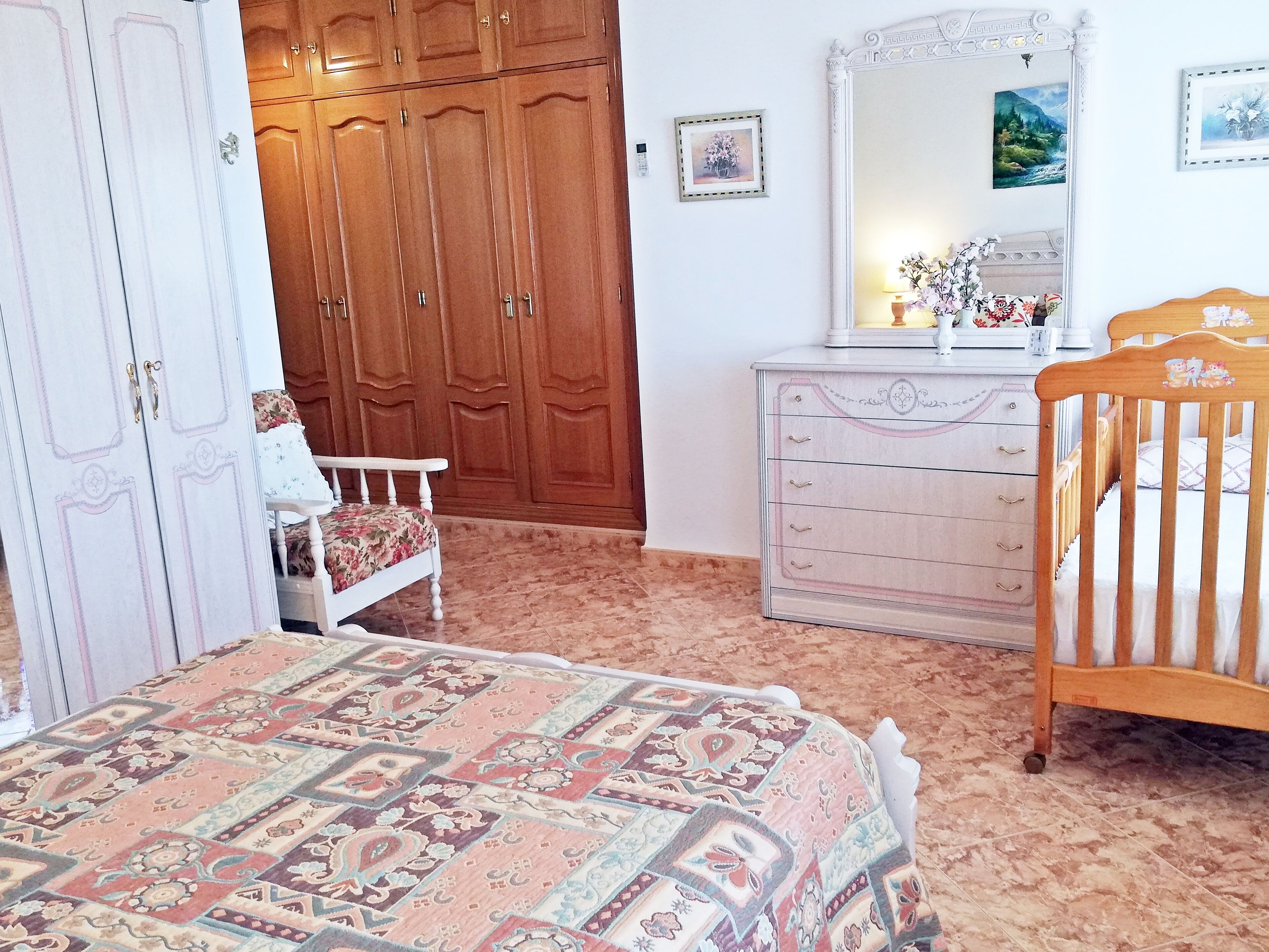 Ein Schlafzimmer mit einem Bett, einem Holzschrank, einer Kommode und einem Stuhl.