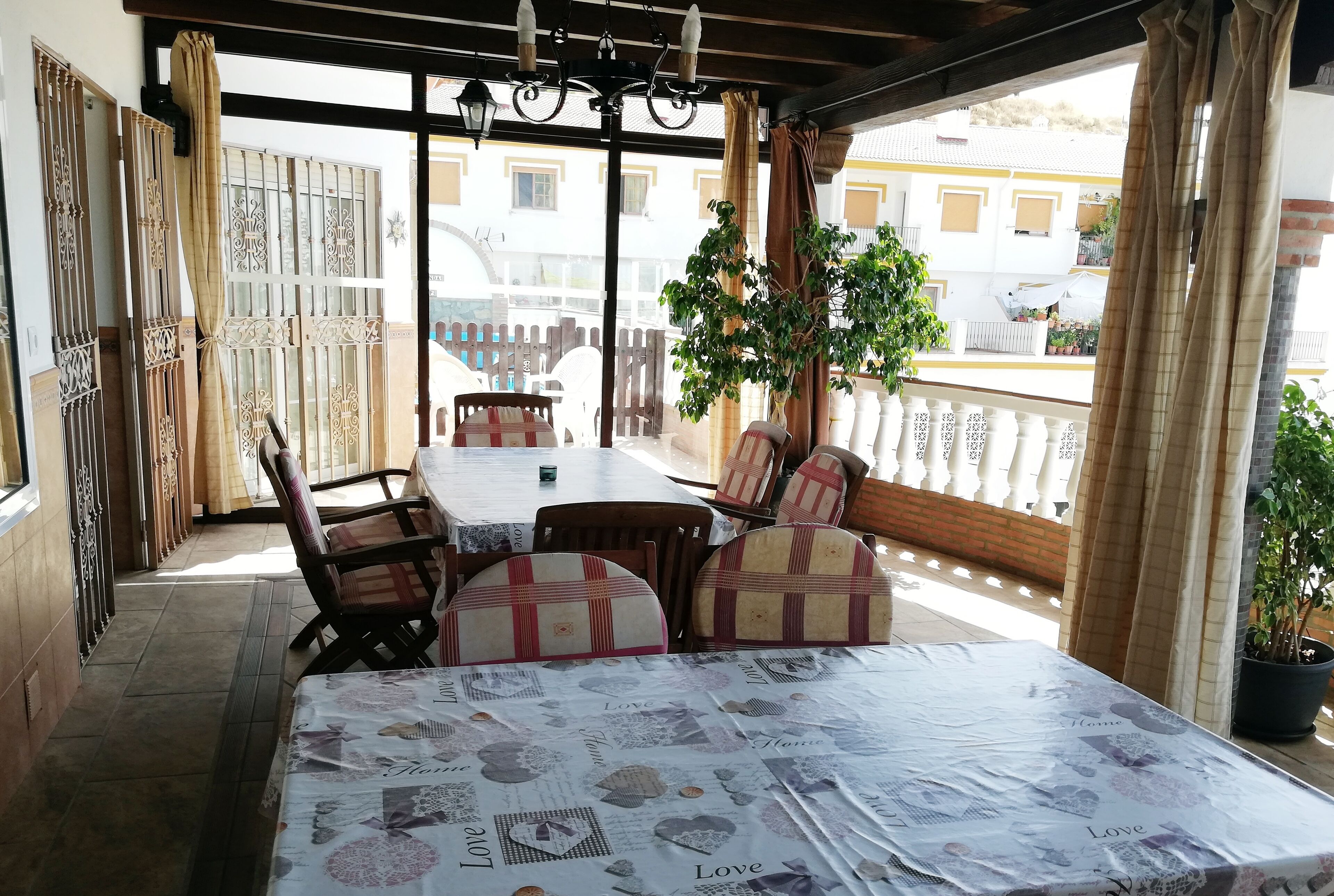 Un comedor con una mesa dispuesta para cuatro personas, rodeada de sillas con cojines estampados.