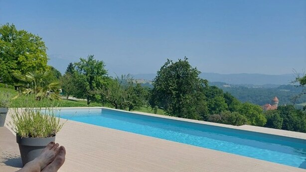 Un espace aménagé au bord de la piscine avec des chaises longues, un téléphone intelligent posé sur une serviette et une plante en pot.