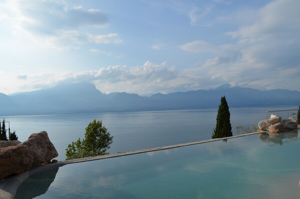Piscina infinita com vista para um lago tranquilo e montanhas ao fundo.