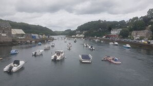 A harbor with various boats docked along the waterfront, surrounded by buildings and hills. - Beautiful Country Cottage (Looe)